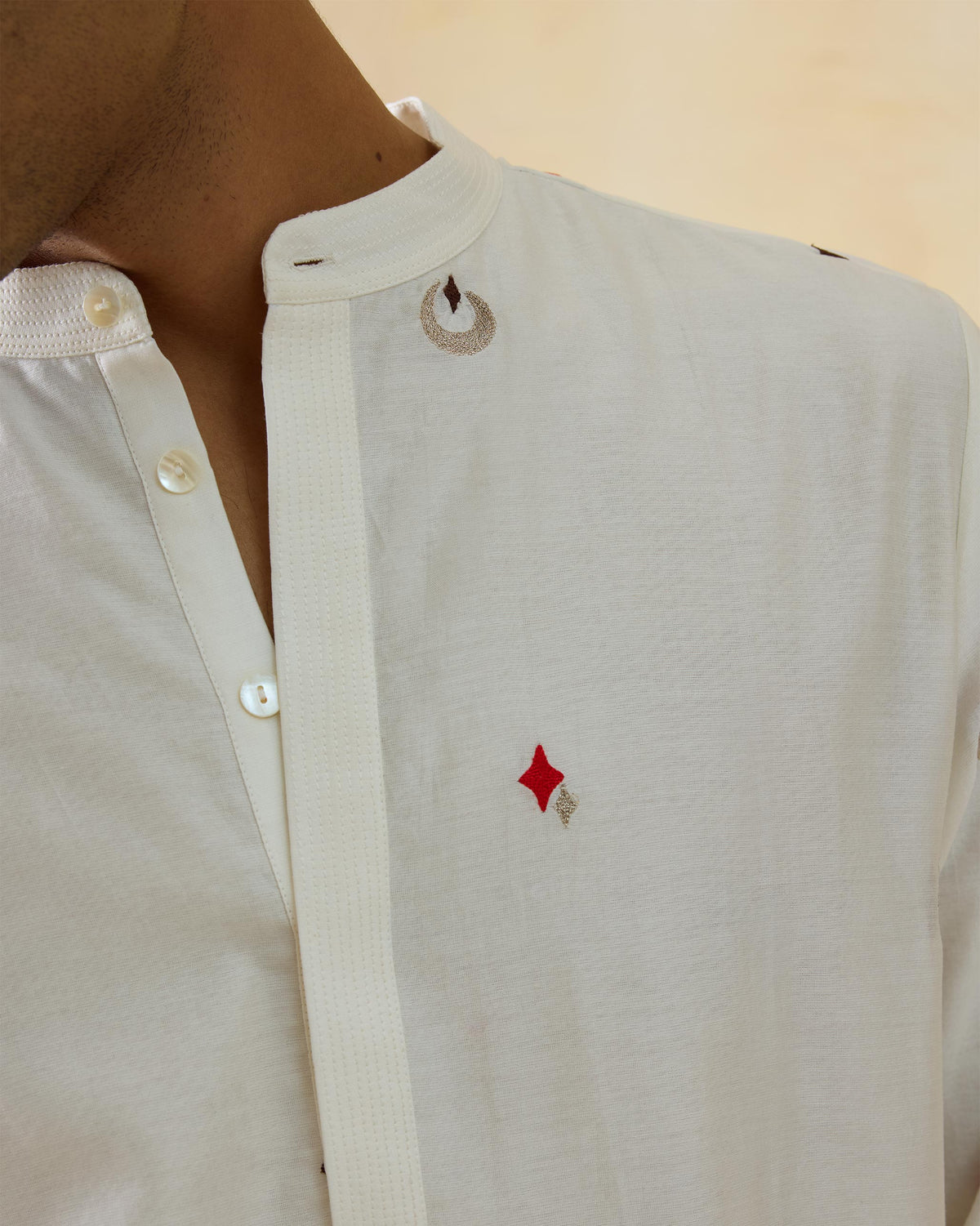 Close-up of an ivory Neckband Kurta showing the band collar and red diamond embroidery.