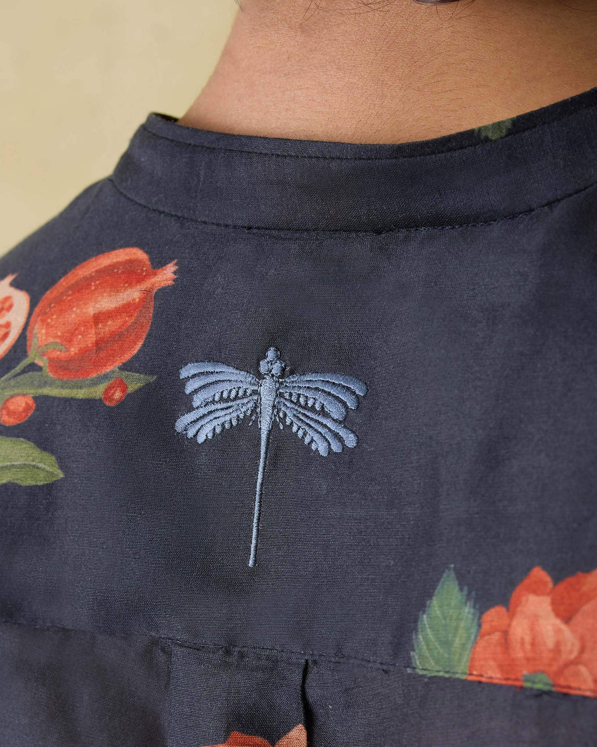 Close-up of a blue dragonfly on the back of a charcoal Ibn kurta.