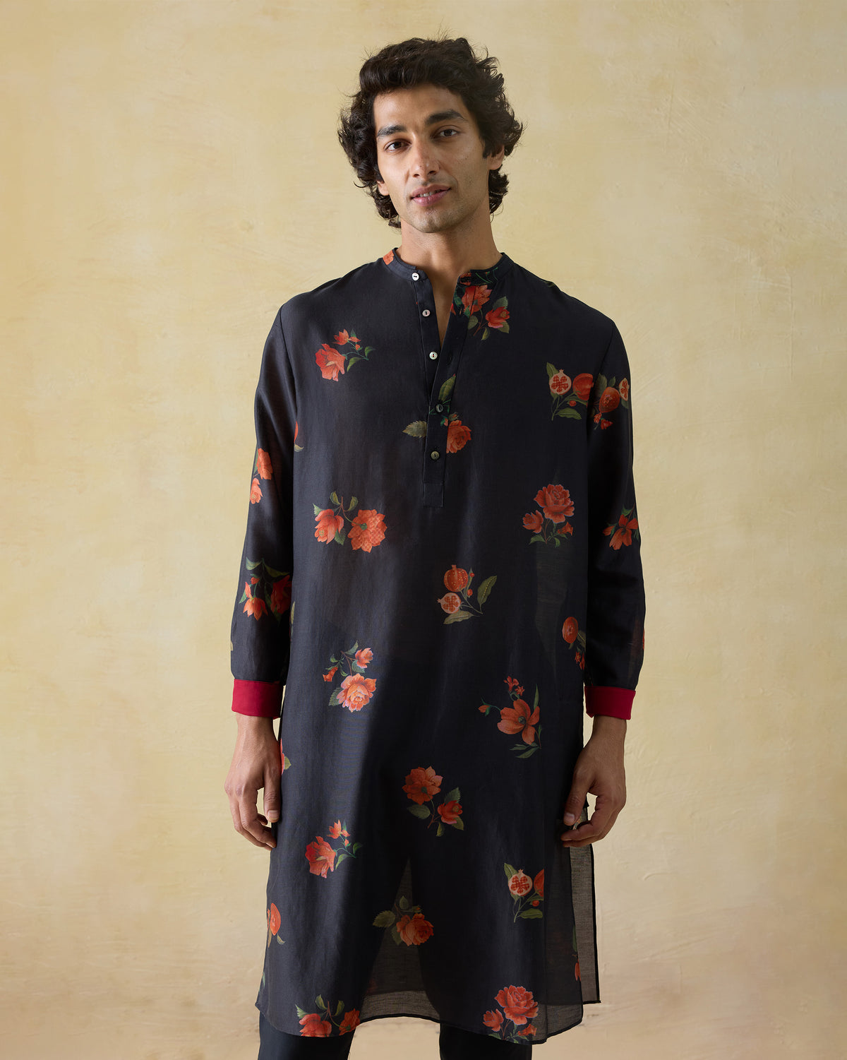 Person wearing a charcoal Ibn kurta with orange floral print and red cuffs.