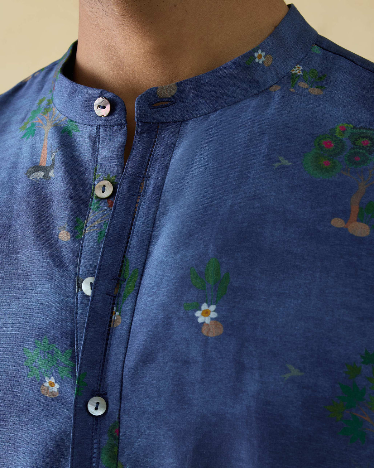 Close-up of a teal blue Astral kurta showing trees and flowers on the placket.