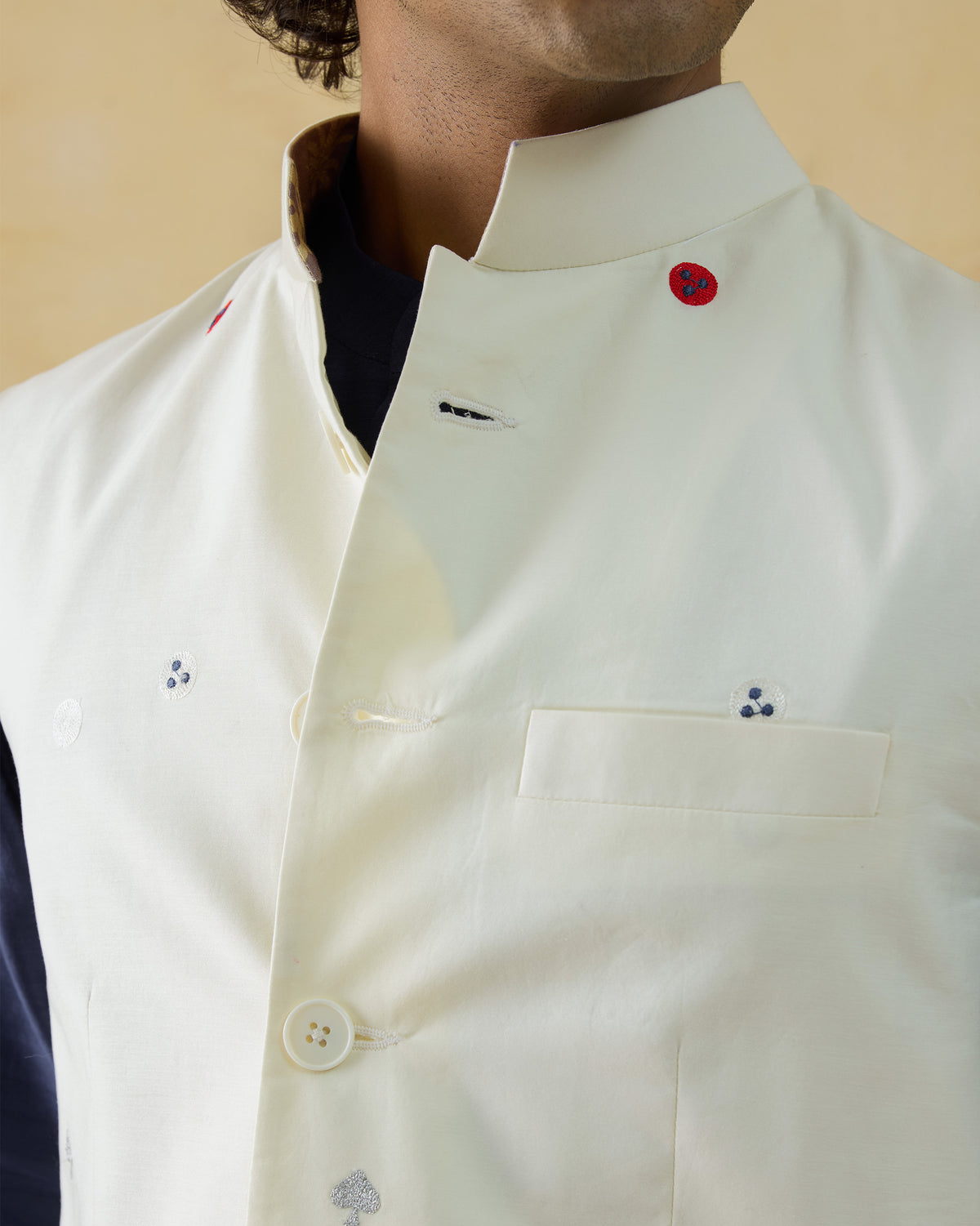 Close-up of an ivory Nehru Jacket with a Nehru collar and red embroidered dots.