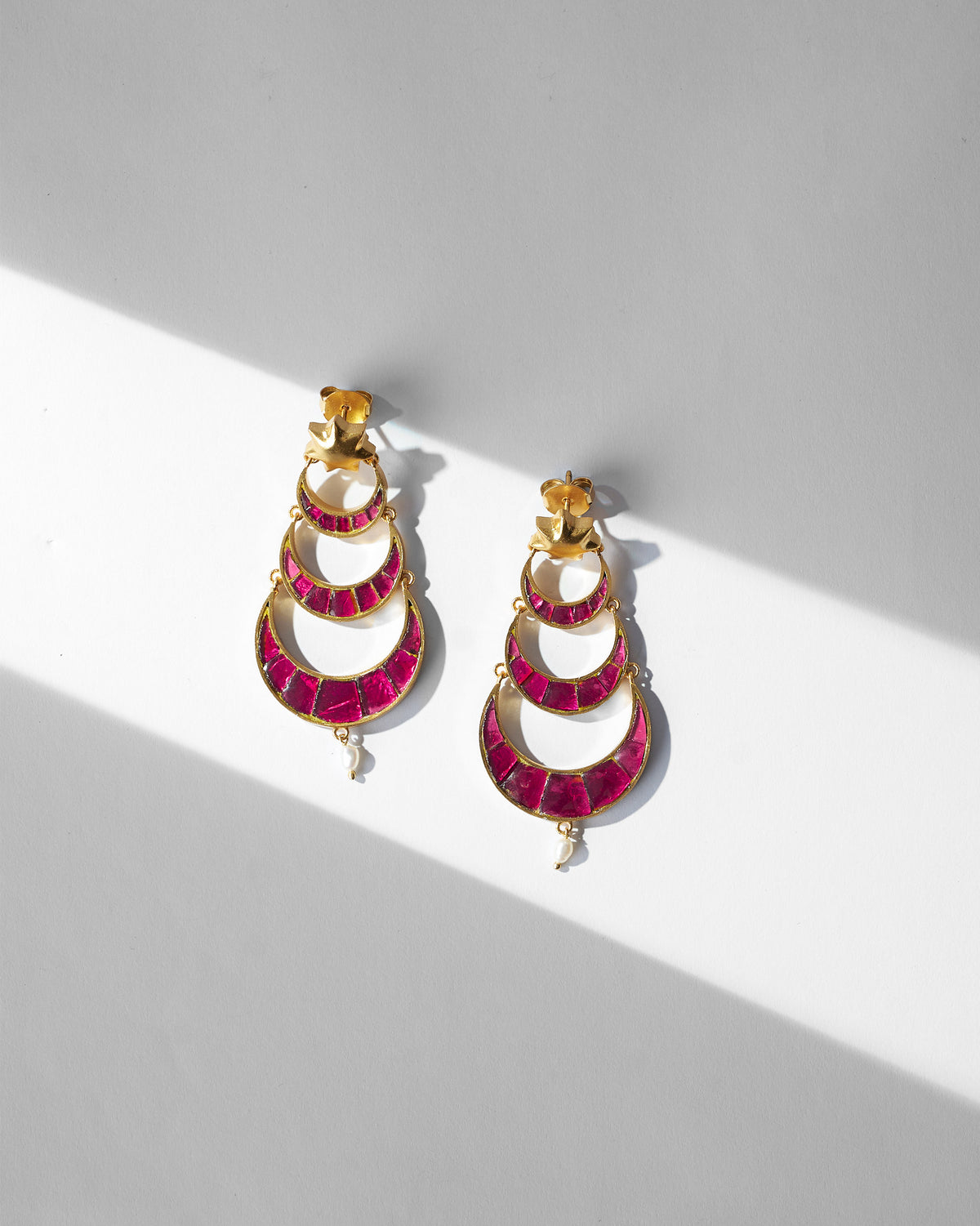 Pair of Gul-Chand Earrings with pink stone tiers, laid flat.
