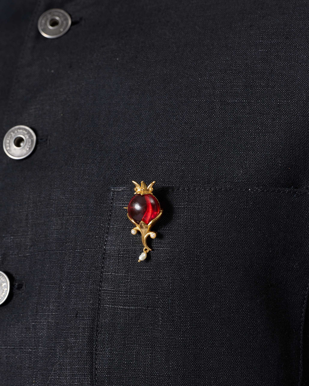 Pom Pearl Brooch with a red stone and pearl drops pinned to a black shirt.