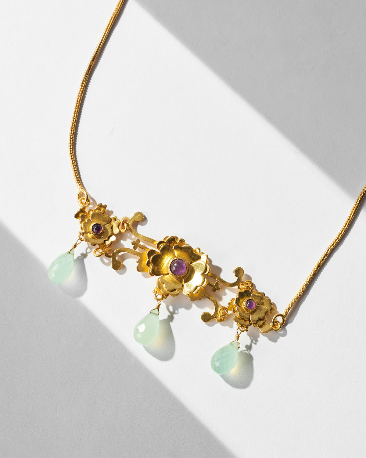 Close-up of a gold Kesar choker with purple stones and pale green drops.