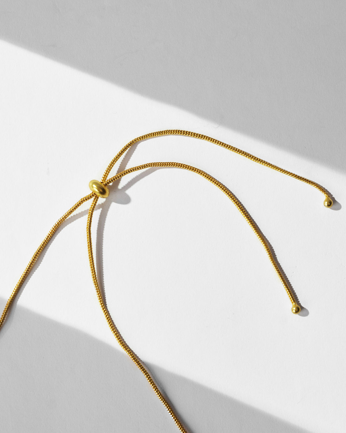 Close-up of the gold adjustable cords and slider of a Kesar choker.