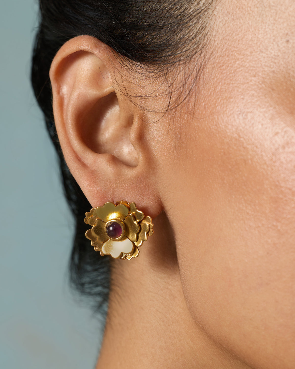 Close-up of a Kesar Phool Stud worn on an ear, showing its purple stone centre.