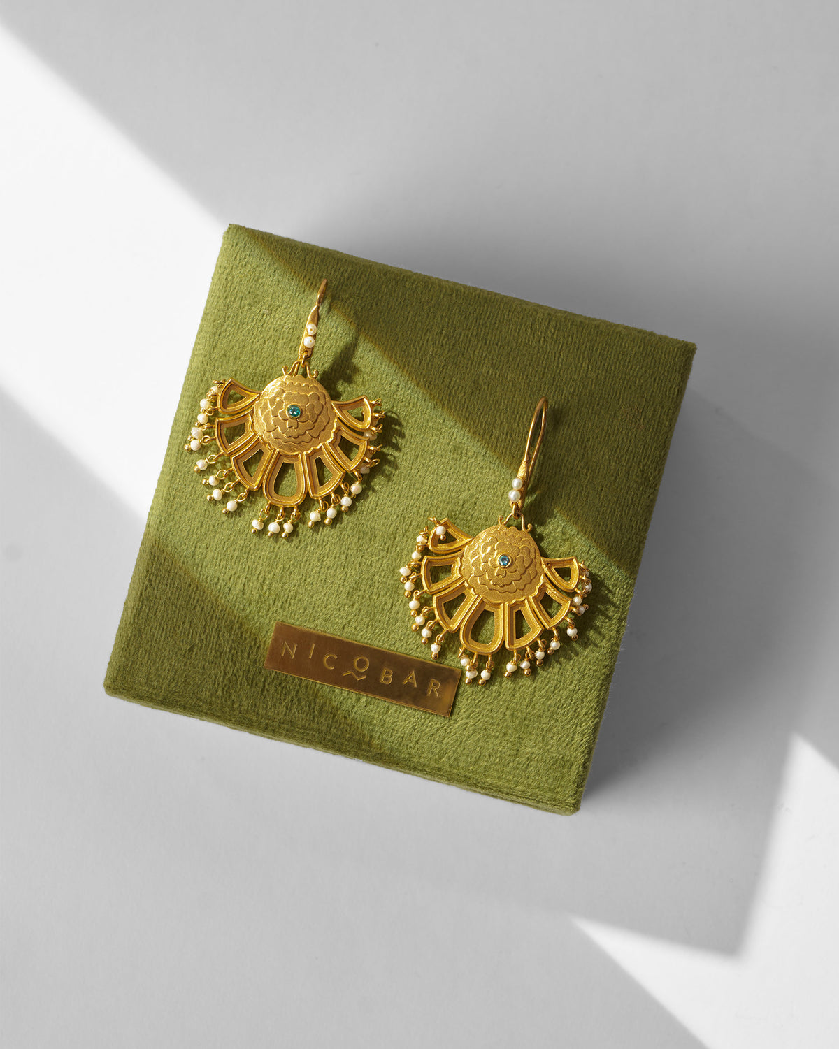 Pair of gold Marigold Earrings on a green gift box.