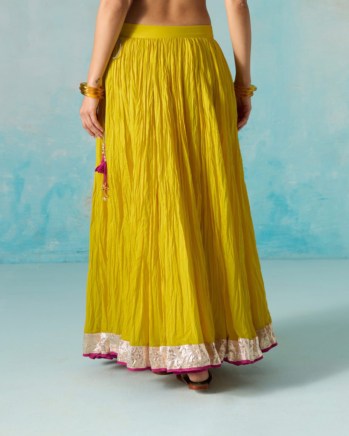 Close-up of the waistband with a sequin button and checked tie on a yellow Berura skirt.