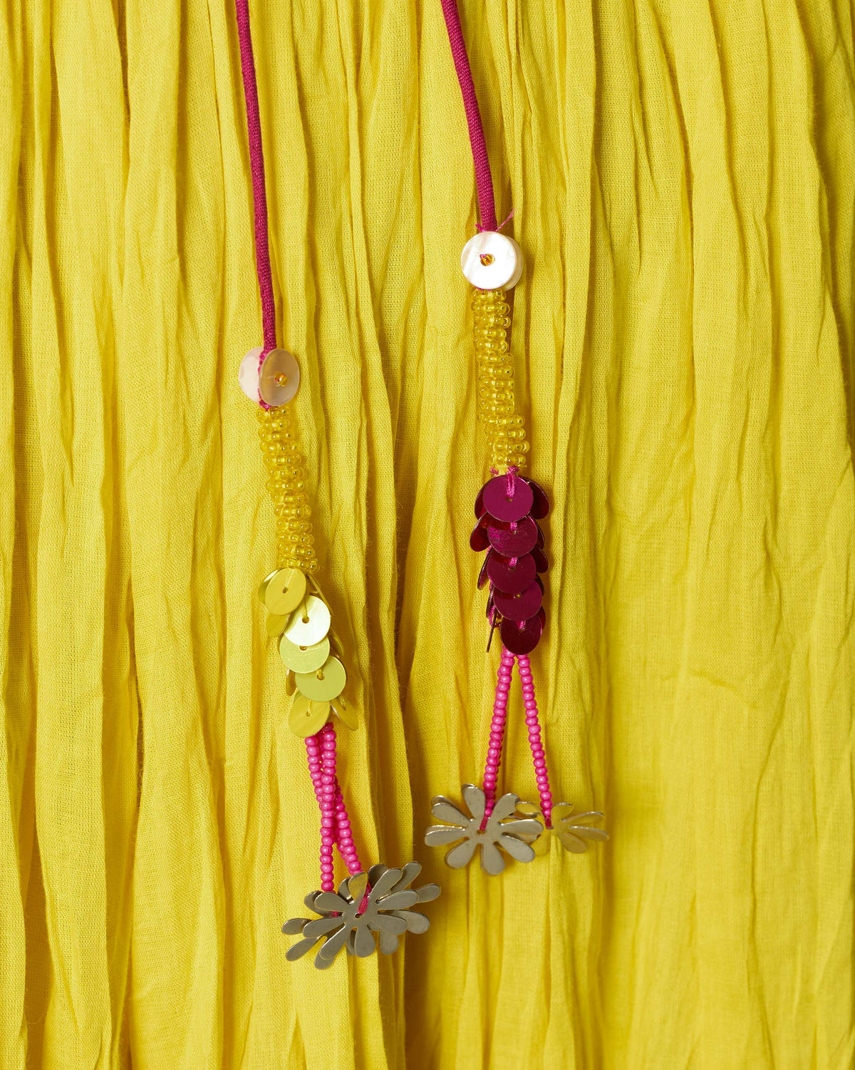 Close-up of beaded tassel ties with sequins and metal flower charms.