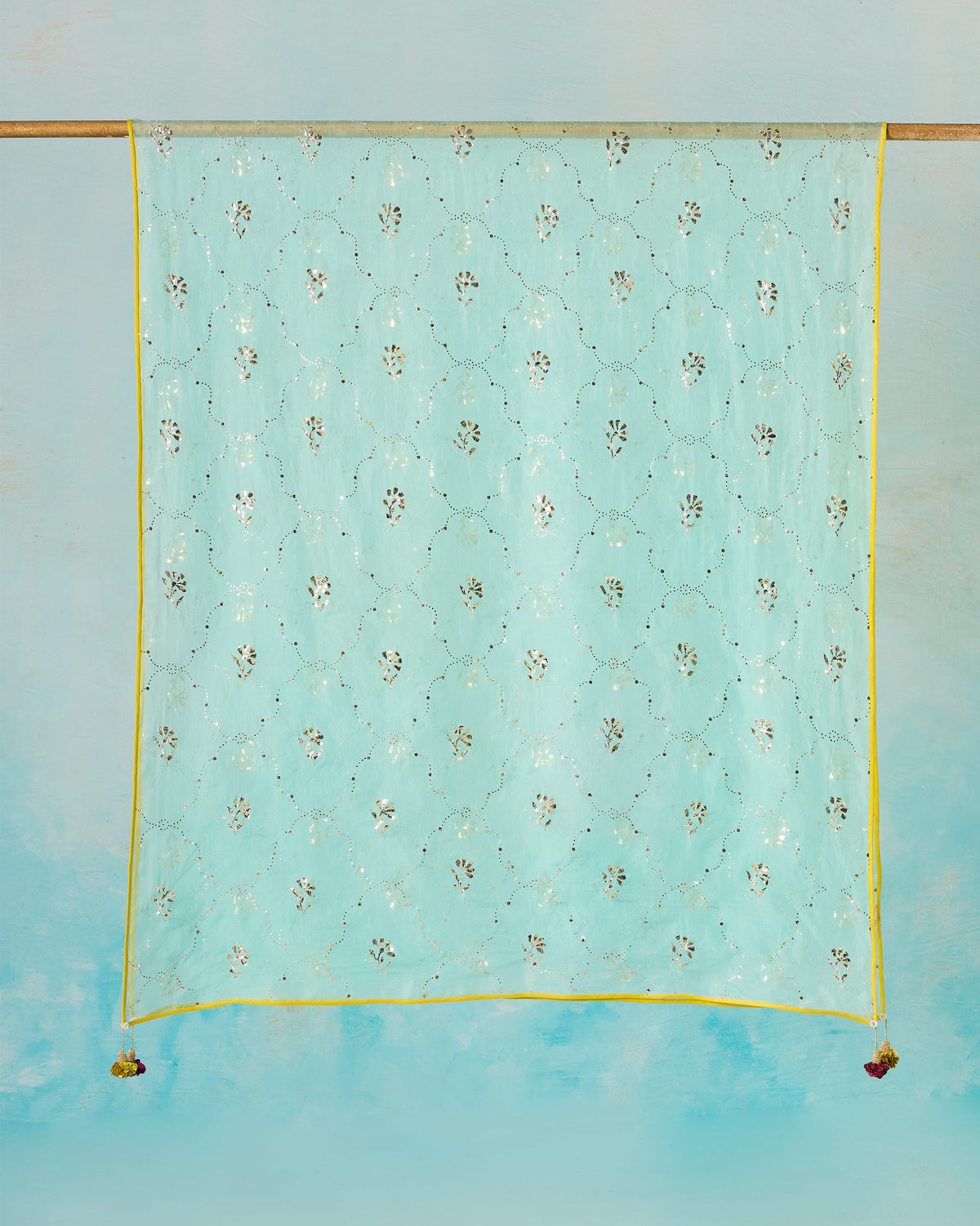 Sea foam Adaa Dupatta with silver mukaish and a yellow border hanging flat.