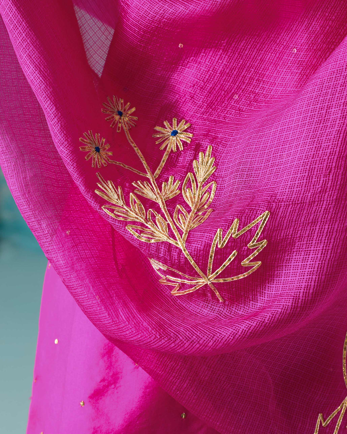 Close-up of gold sprig embroidery on a magenta Ishara dupatta.