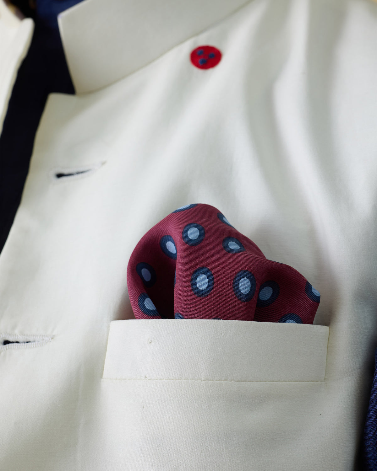 Pipit silk pocket square with blue polka dots worn in a breast pocket.