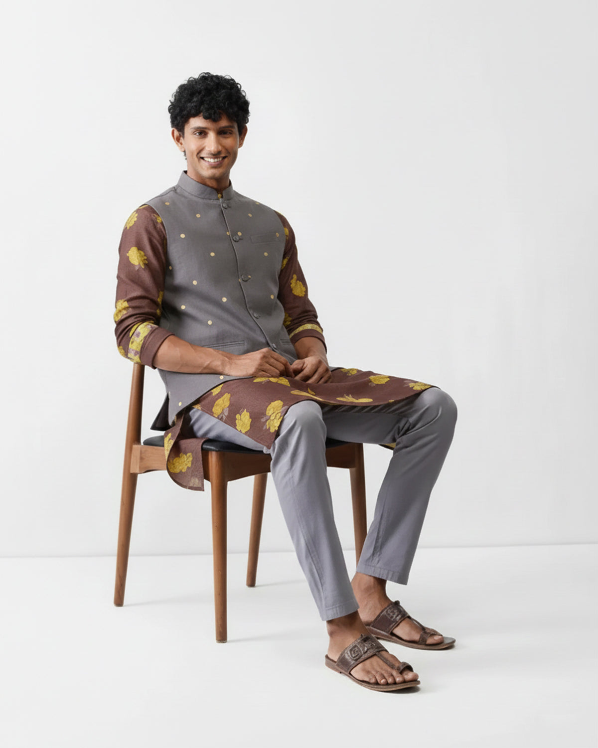 Person seated wearing a charcoal Nehru jacket with gold embroidered dots.