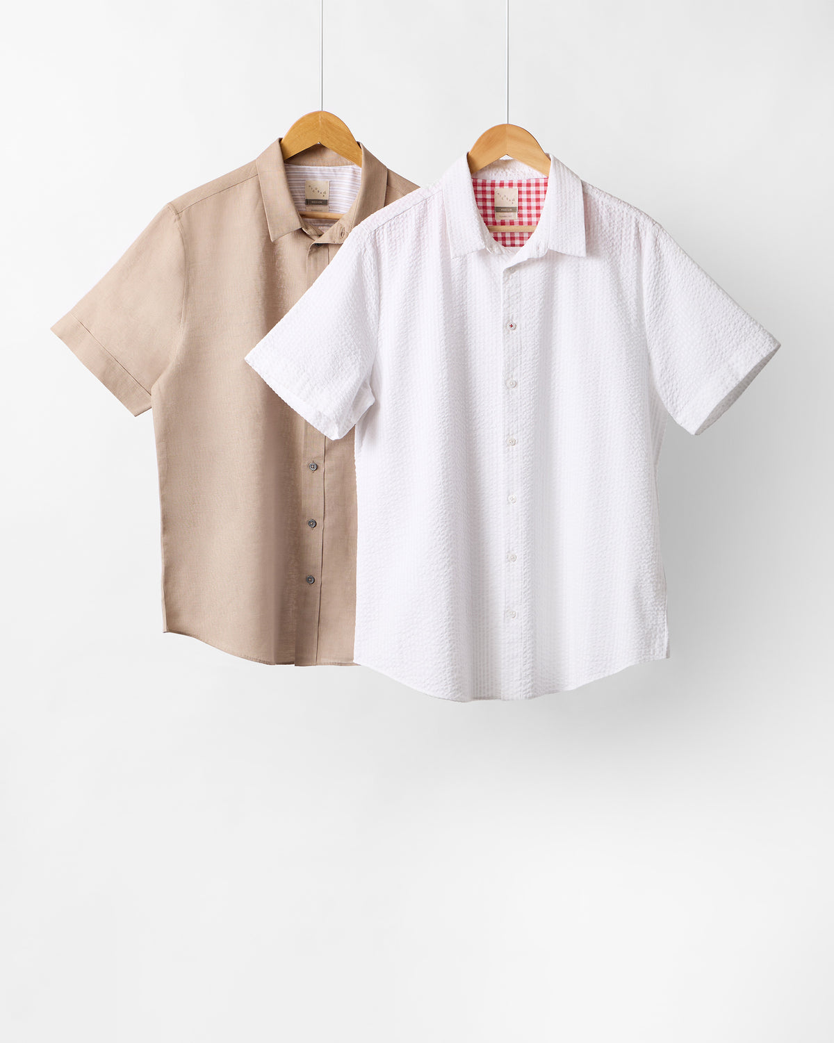 Beige and white half sleeve shirts hanging as a set.