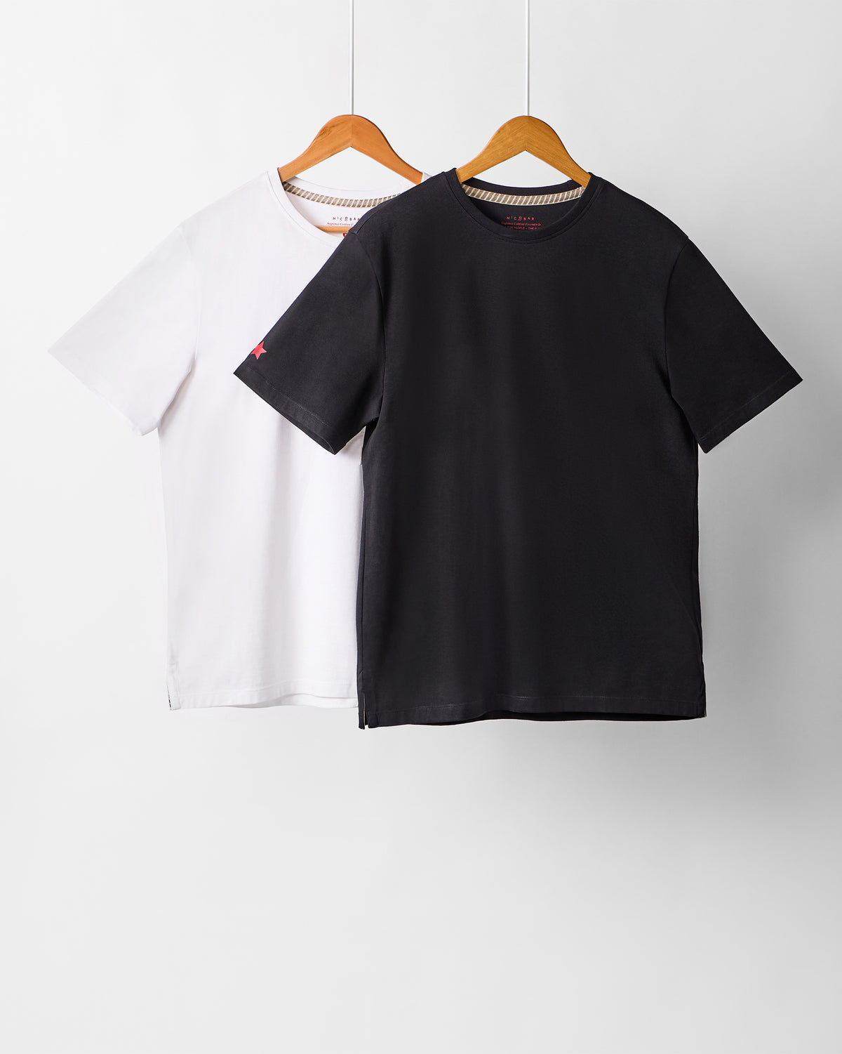 Black and white Everyday Essentials t-shirts hanging as a set.