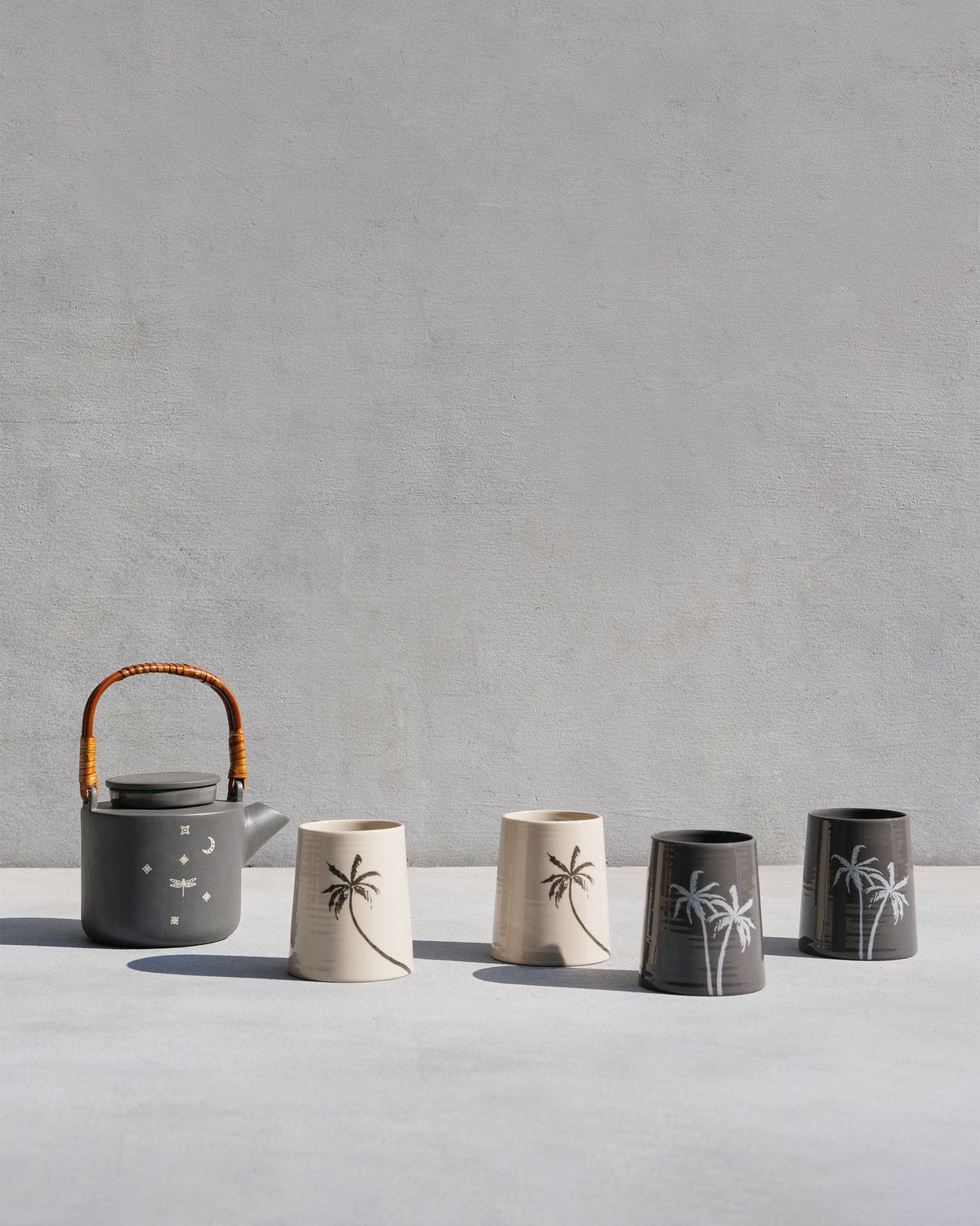 Taramandal teapot and four palm kulhars lined up in cream and charcoal.