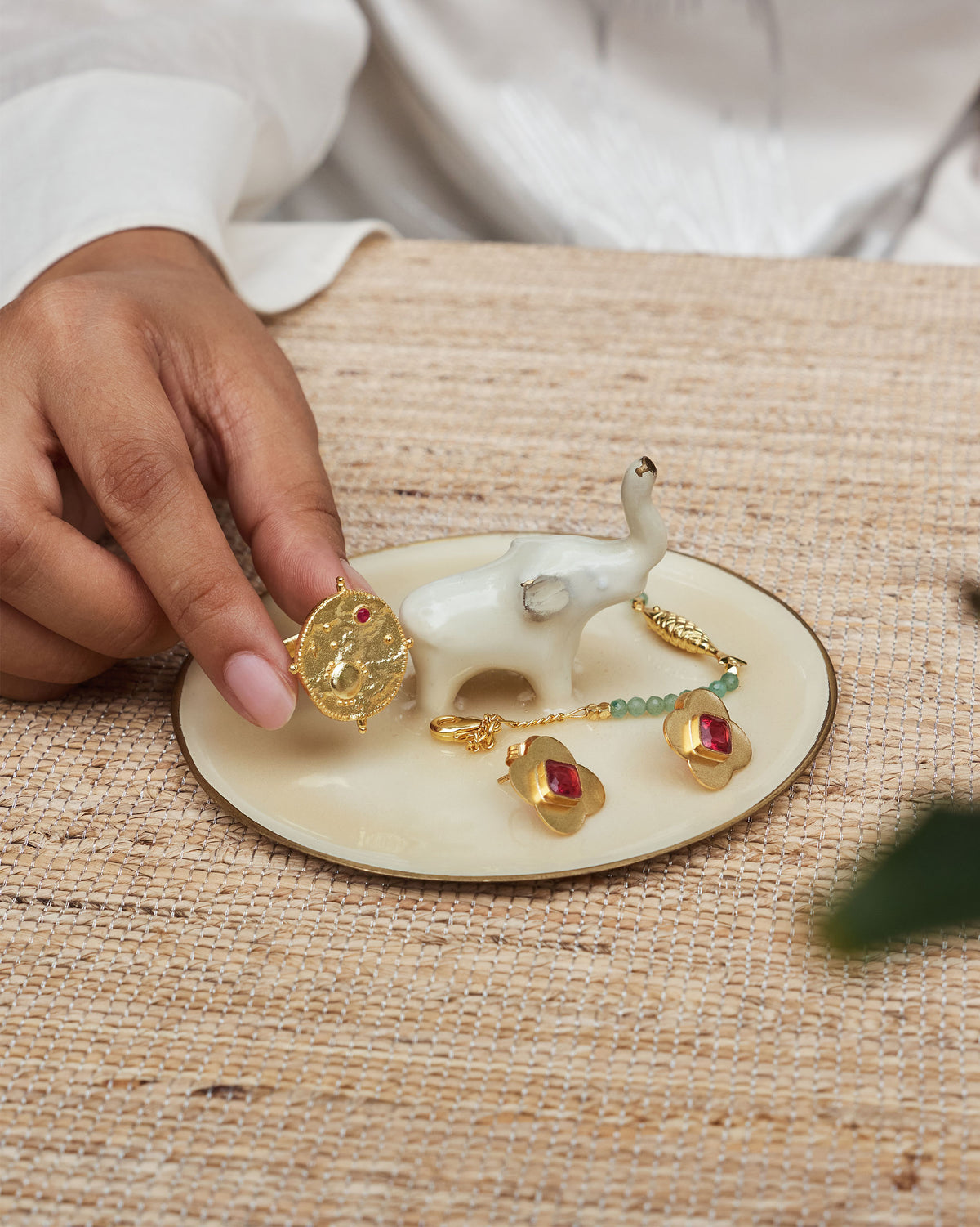 Person placing a ring on an Ele trinket tray with a white elephant figure.
