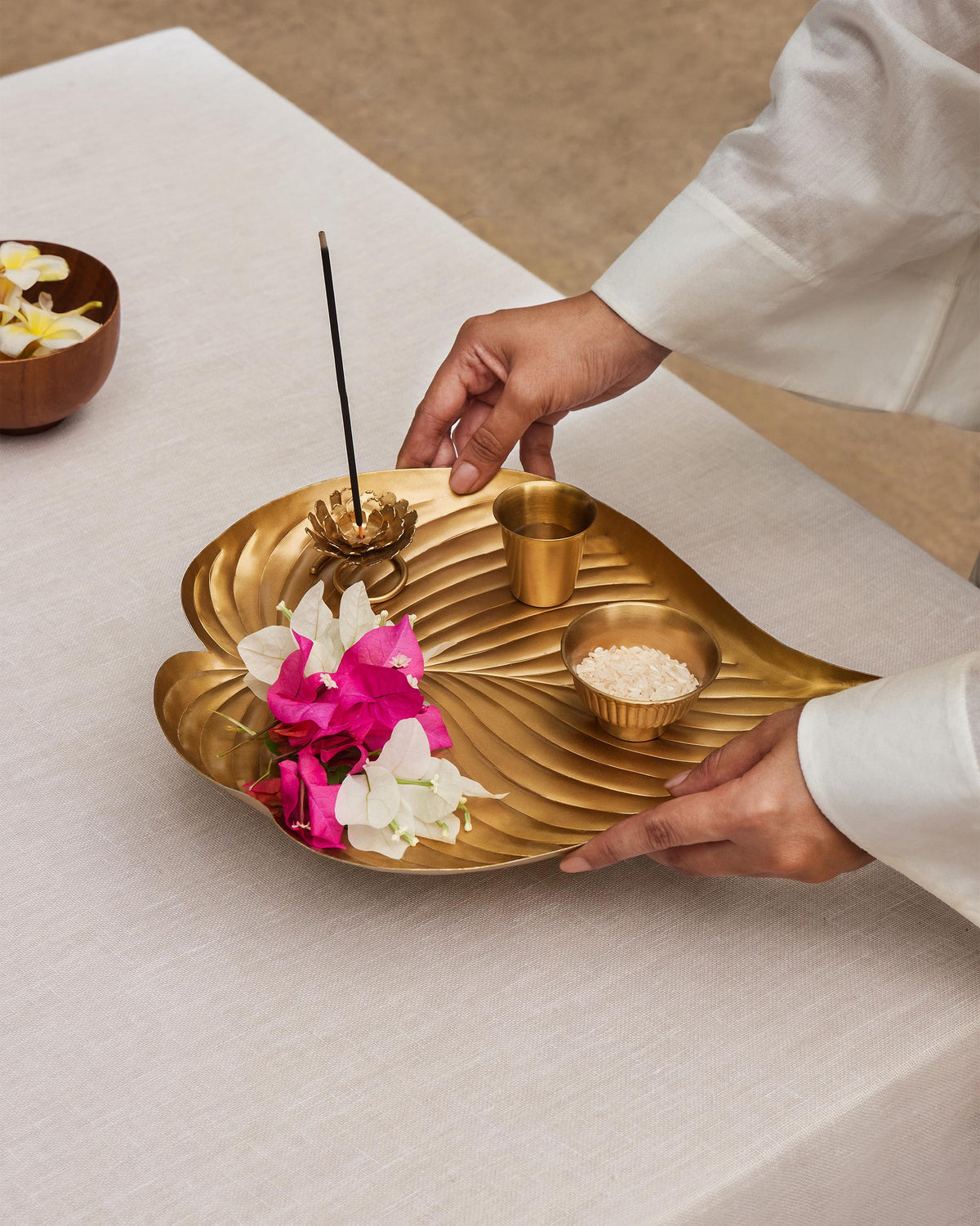 Asfar brass leaf pooja tray held with incense holder and bowls.