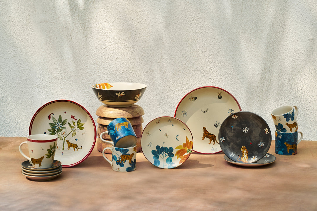 Nadi tea plates displayed among mugs and bowls with tiger motifs.