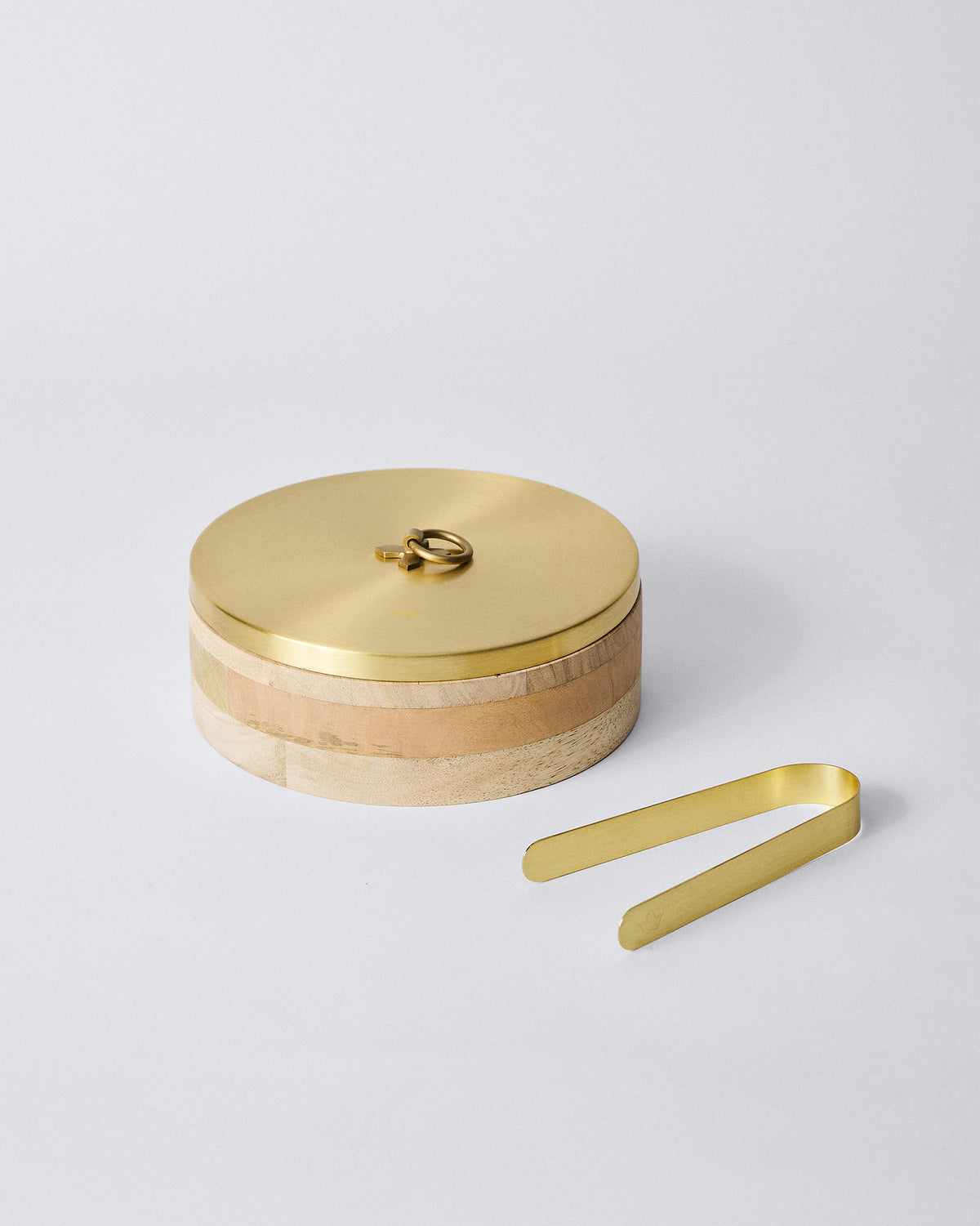 Wooden roti box with brass lid and matching brass tongs beside it.