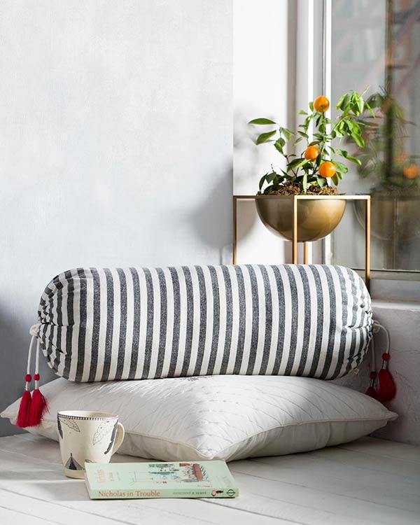 Black and white striped bolster cover with pink tassels on a cushion.