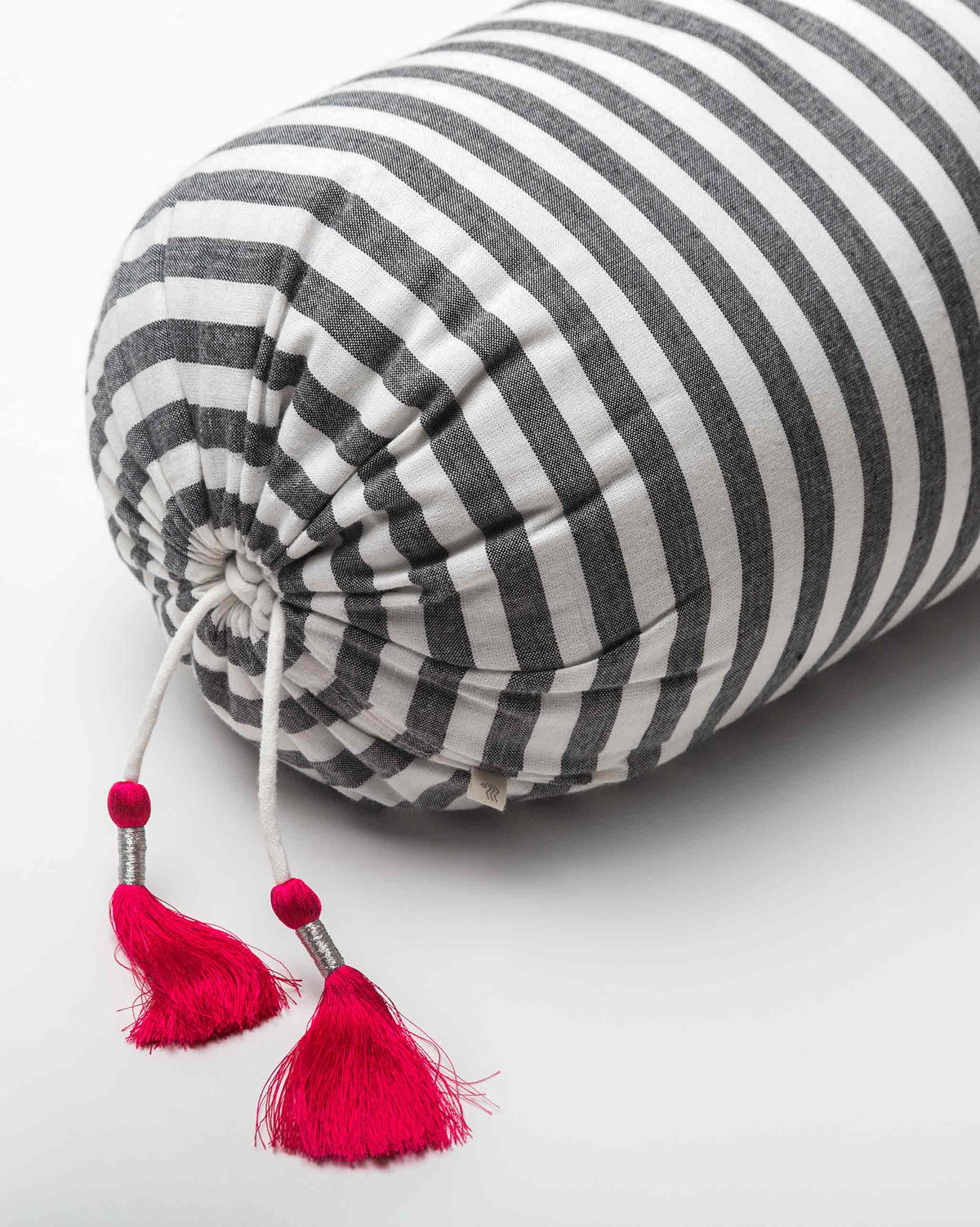Close-up of pink tassels on a black and white striped bolster cover.