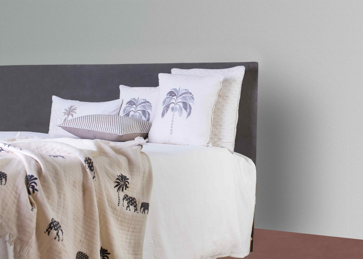 Colombo charcoal throw with elephant and palm print on a made bed.