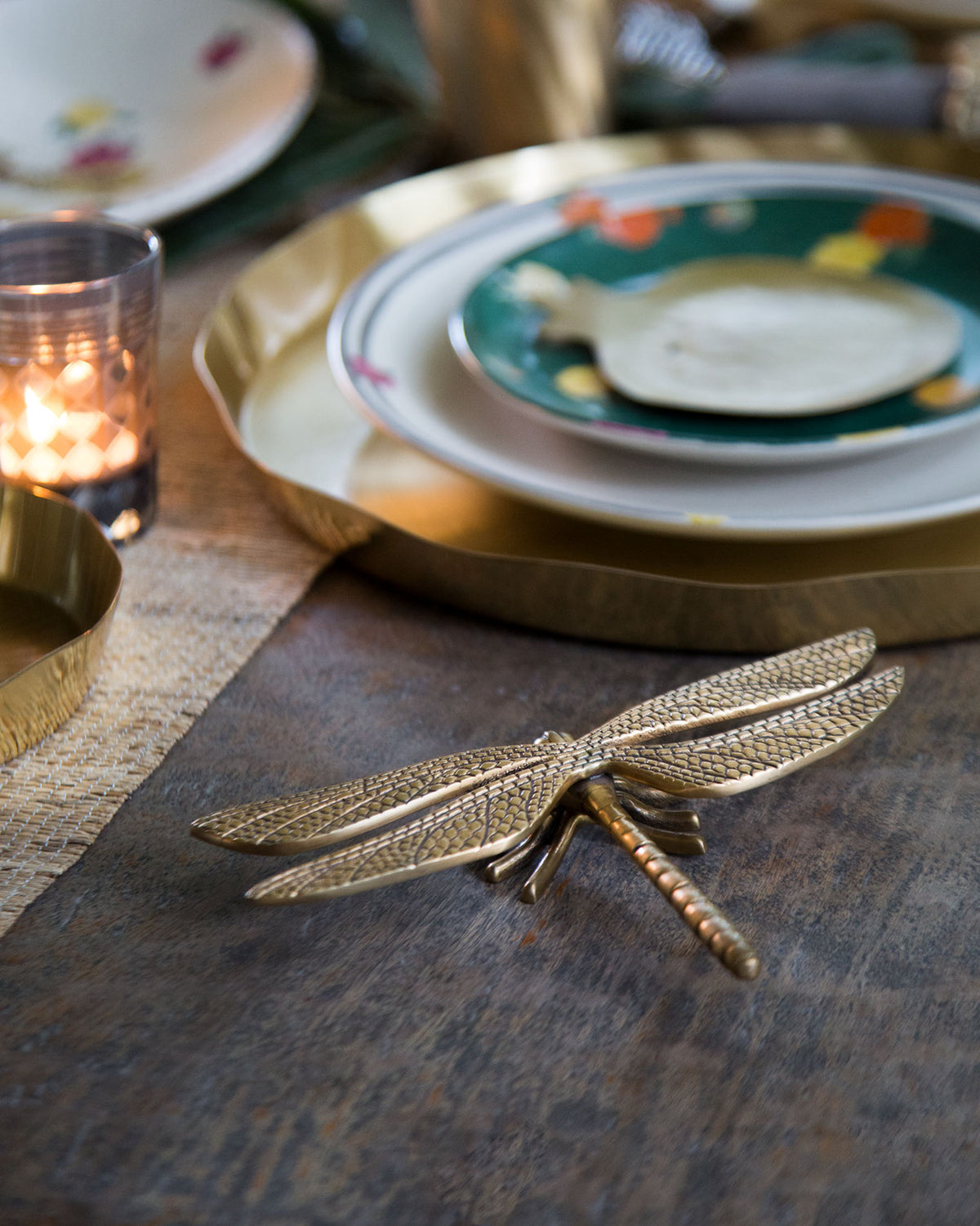 Brass dragonfly accent piece styled on a dining table.