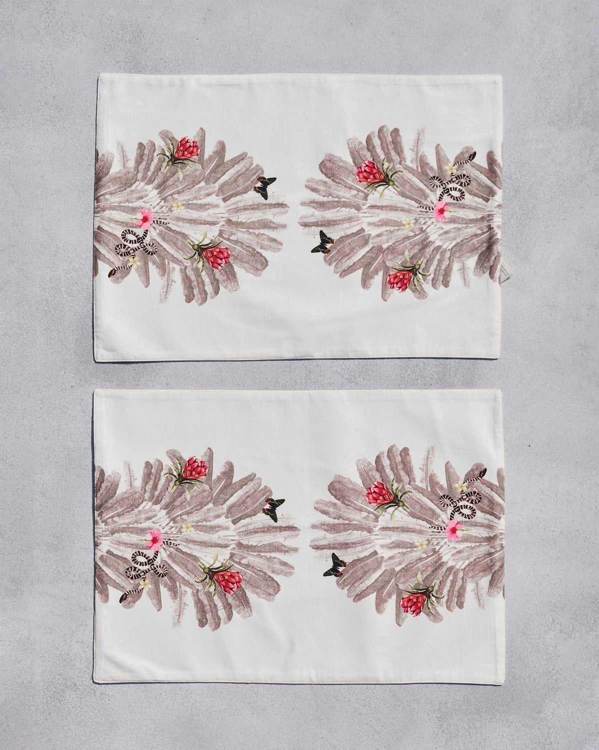 Overhead view of two Ravenala Placemats with a red flower and leaf print.