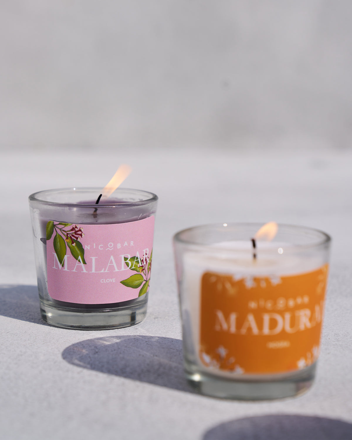 Close-up of a lit Malabar clove Trio Candle votive with purple wax.