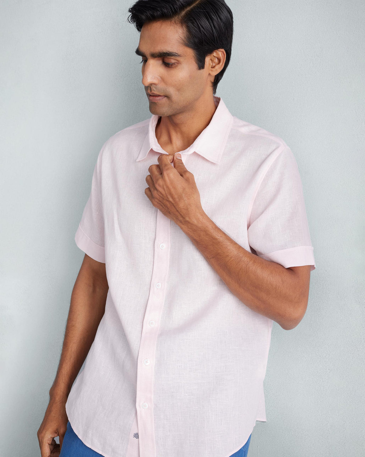 Person wearing a pink half sleeve shirt with a button front and collar.
