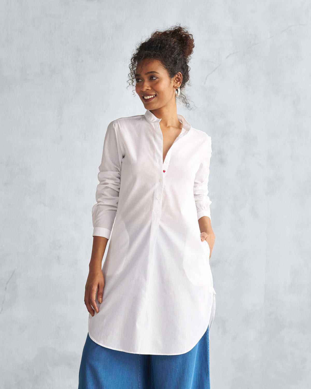 Person wearing a white mid-length kurta with a mandarin collar and red placket detail.