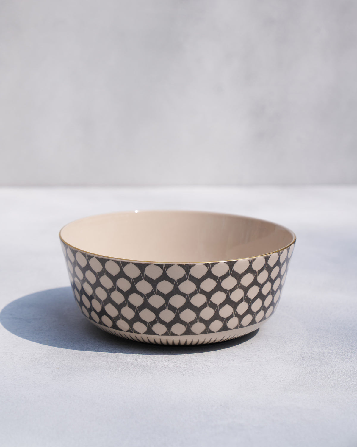 Fez curry bowl with a charcoal teardrop pattern and a gold rim.