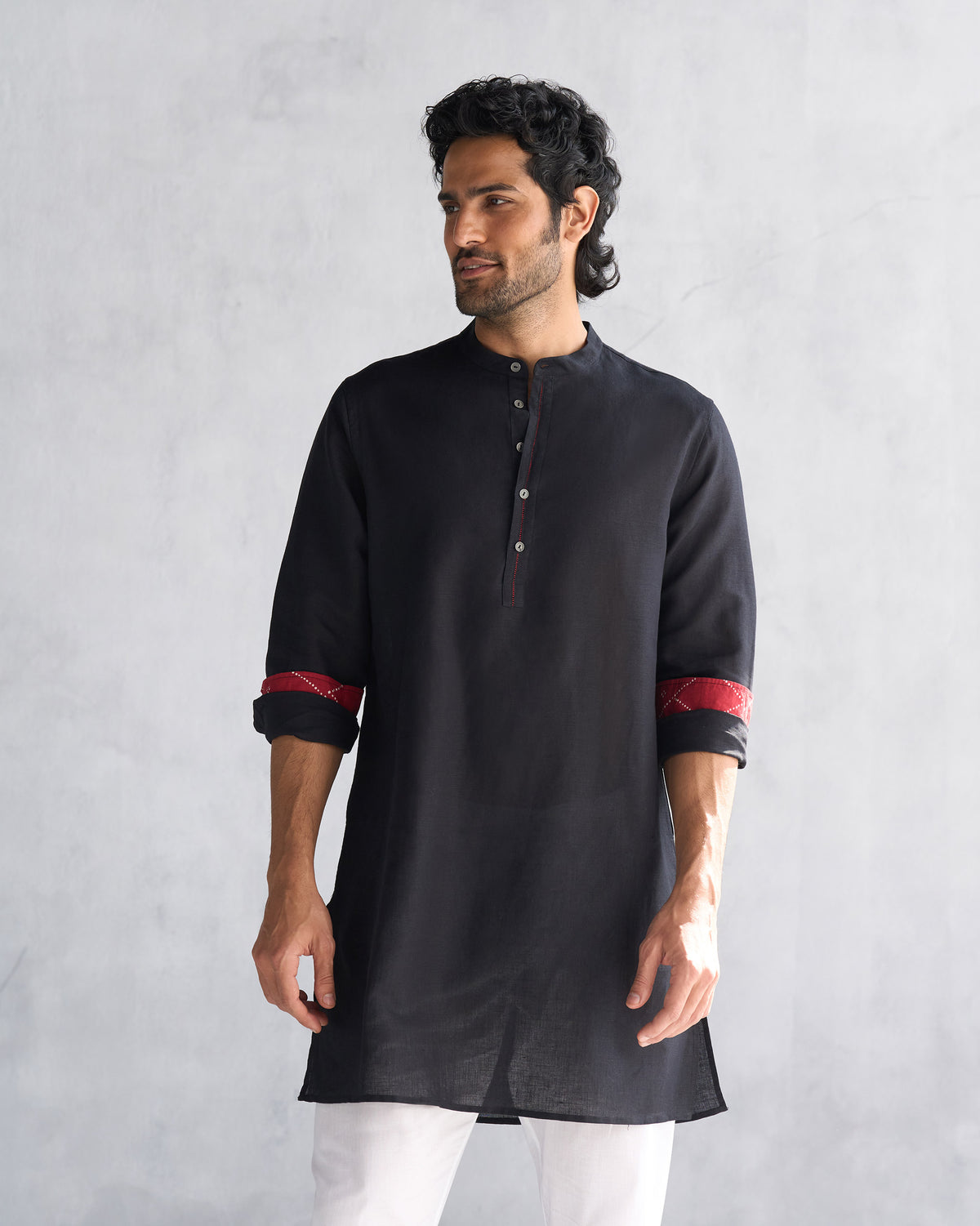 Person wearing a black Chandni Chowk kurta with red contrast cuff lining.