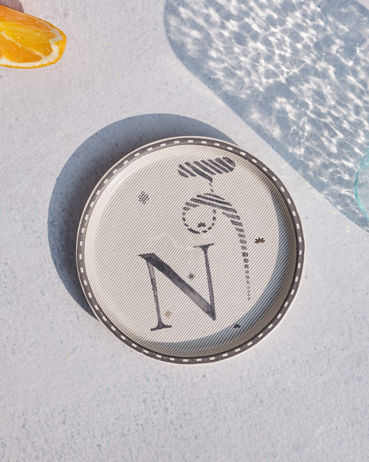 Akshar Coaster with a letter N and a striped glyph on cream.