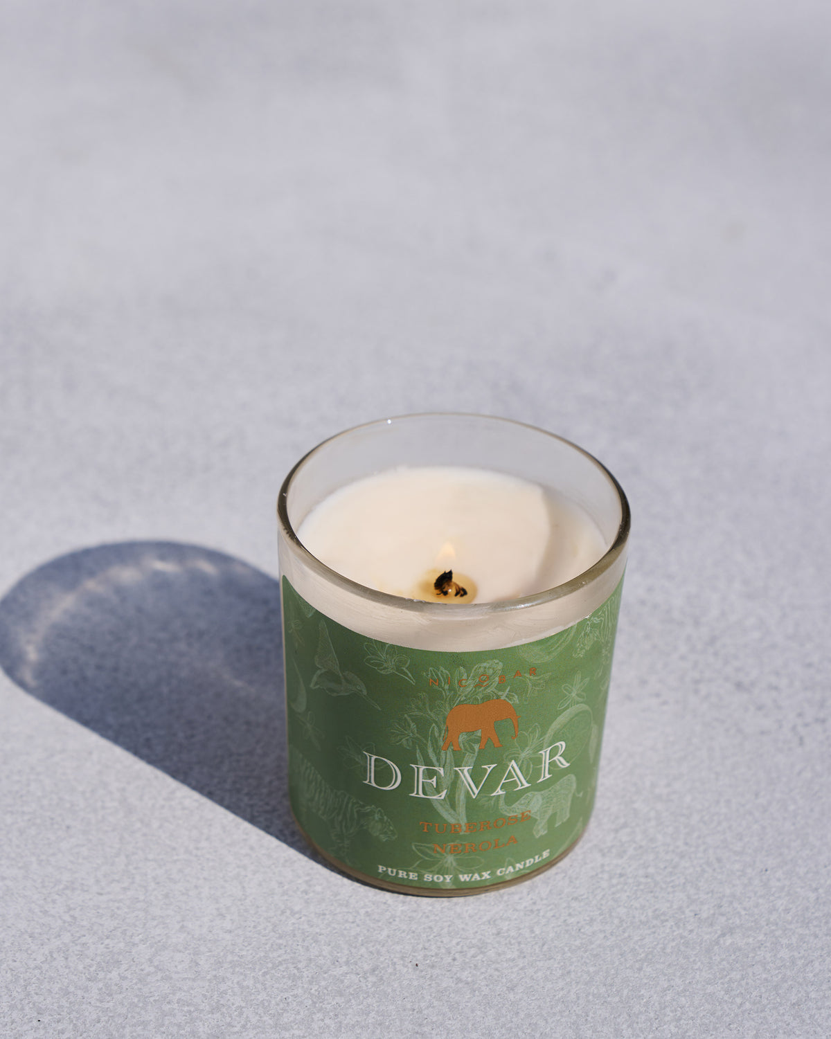 Lit Devar candle in a green glass jar.