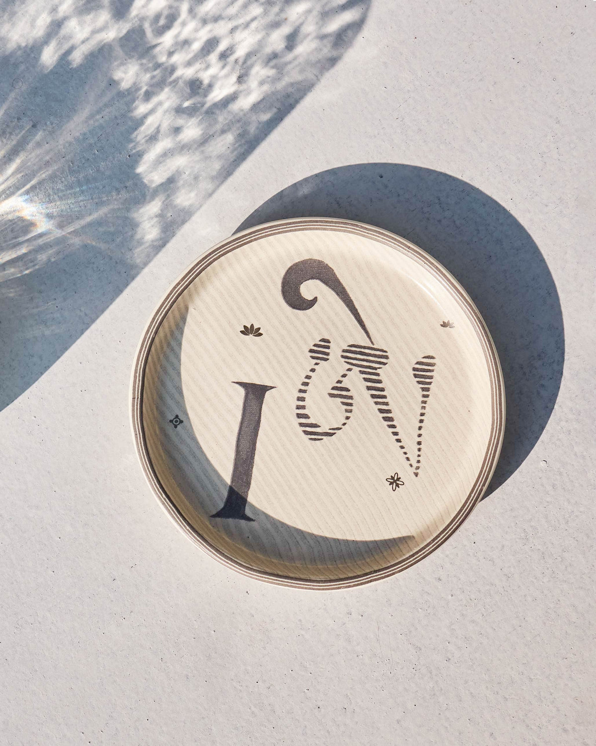 Akshar Coaster with a large letter I on a cream background.