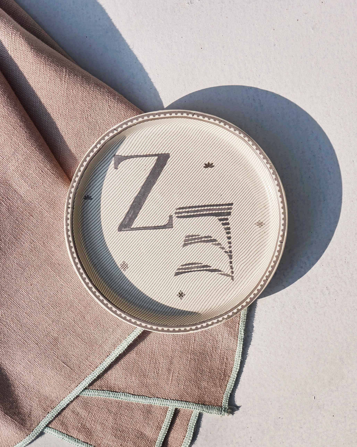 Akshar Coaster - Z laid flat, showing the grey Z glyph and beaded rim.
