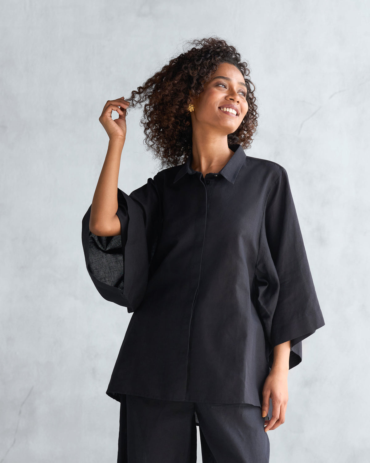 Person wearing a black Drop armhole shirt with wide, dropped sleeves.