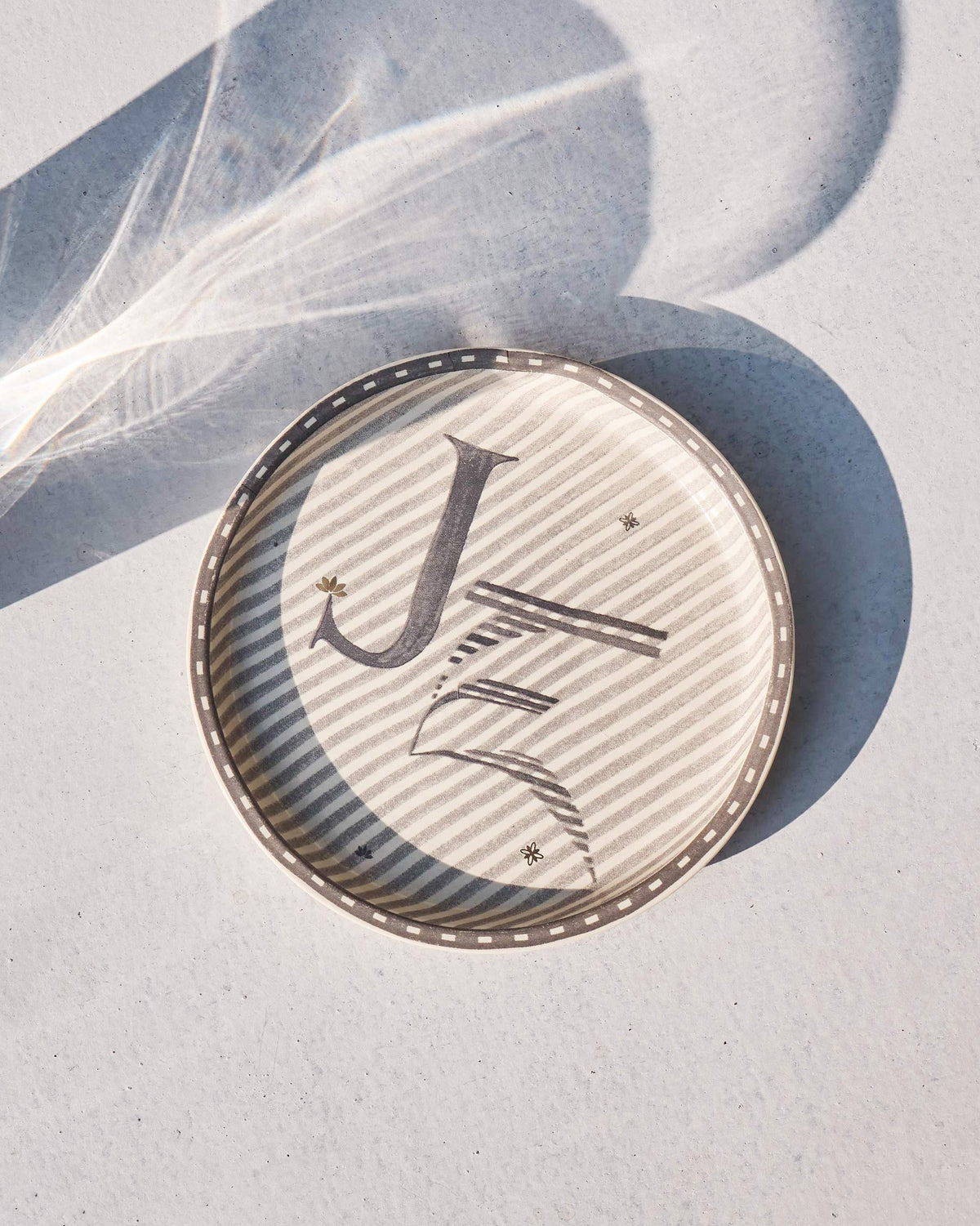 Akshar Coaster with a letter J on grey diagonal stripes.