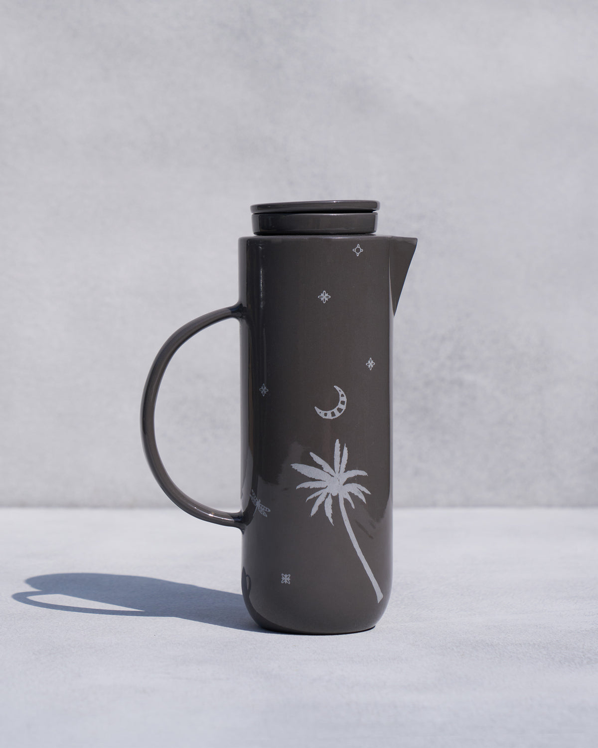 Taramandal Carafe, a dark grey carafe with a white palm, moon and star motif.
