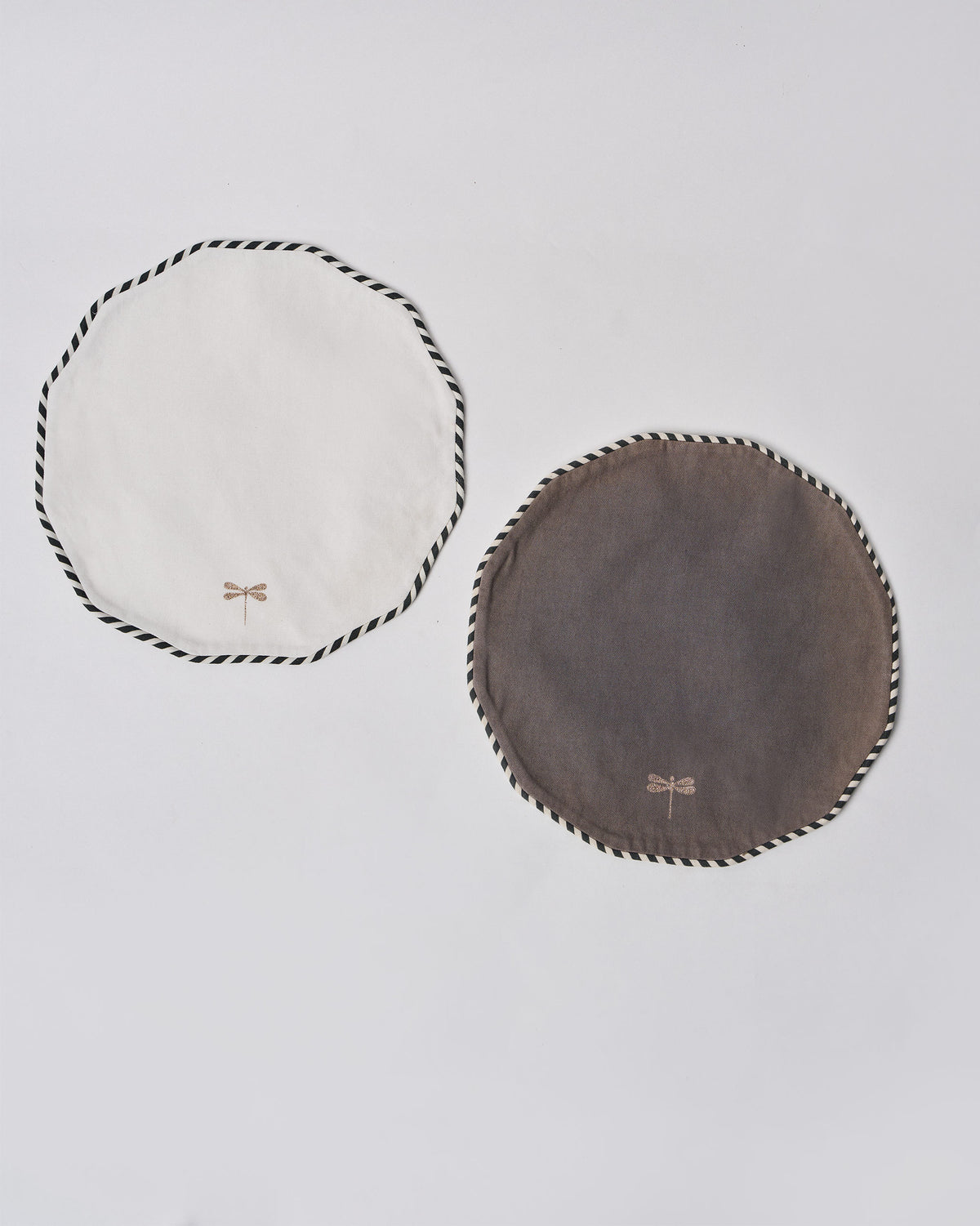 Pair of Myra Placemats in white and grey, each with a dragonfly motif and cord edge.