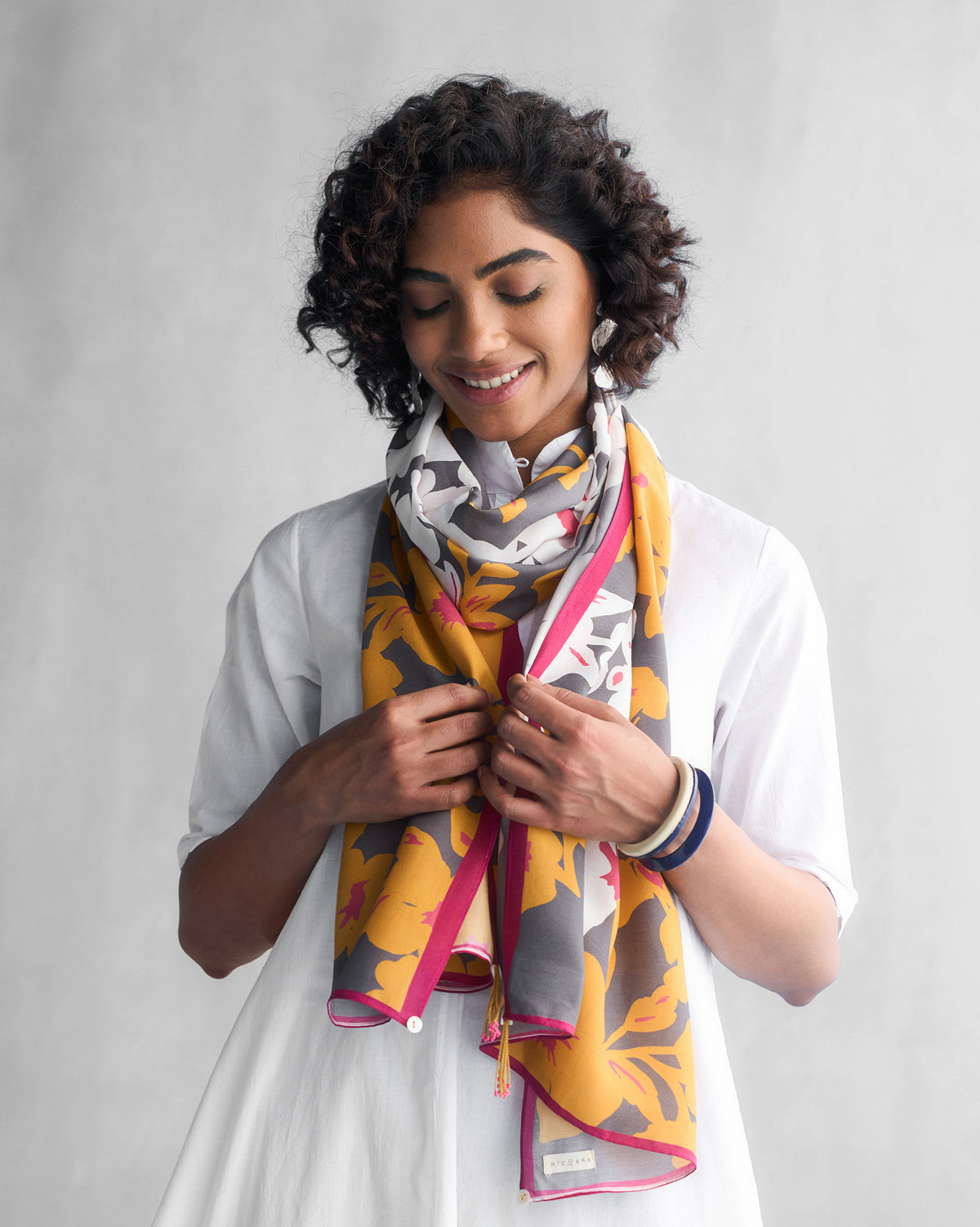 Person wearing a grey and ochre Gudhal scarf with pink edging.