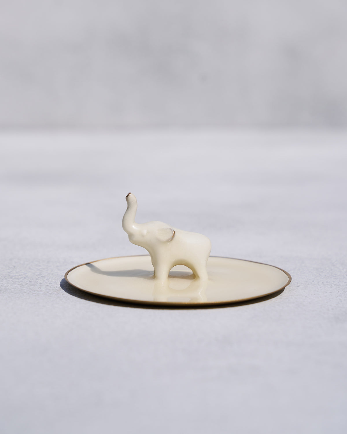 Side view of an Ele trinket tray with a white elephant figure standing on it.