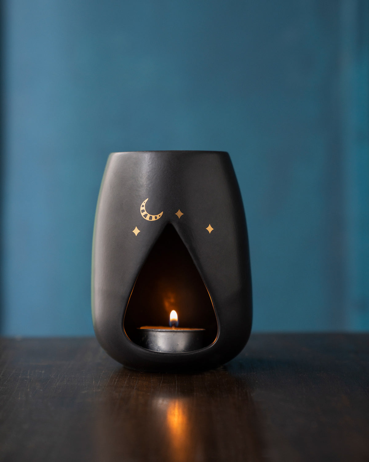Sher diffuser with a gold moon and stars, shown with a lit tea-light.