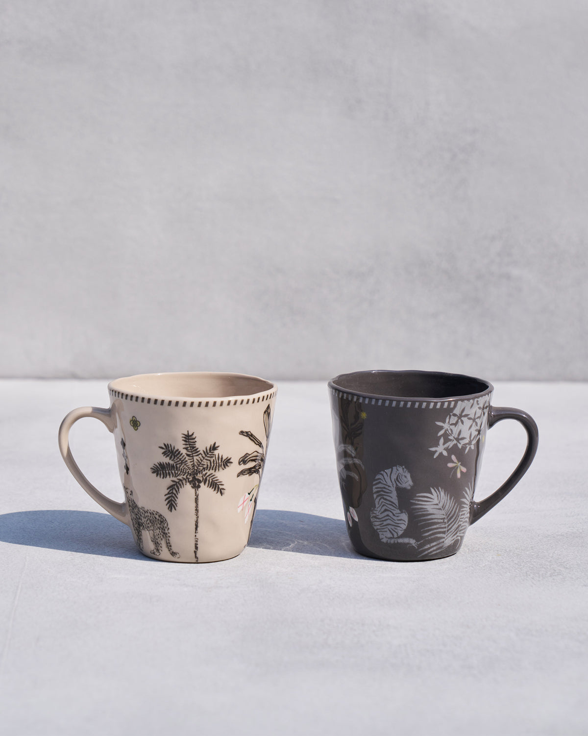 Pair of Malabar conical mugs with leopard-and-palm and tiger motifs.