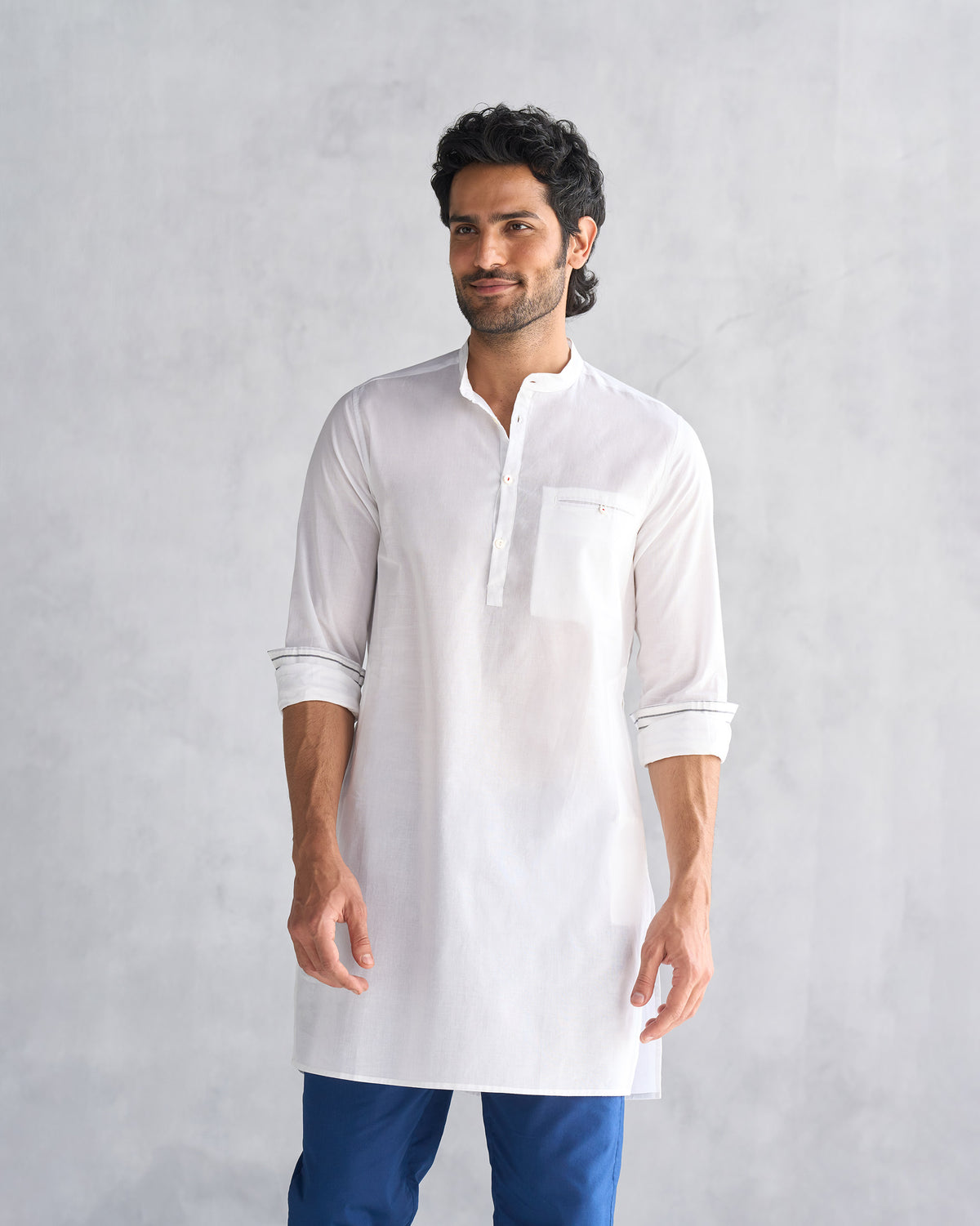 Person wearing a white Pondicherry Kurta with a chest pocket and rolled sleeves.
