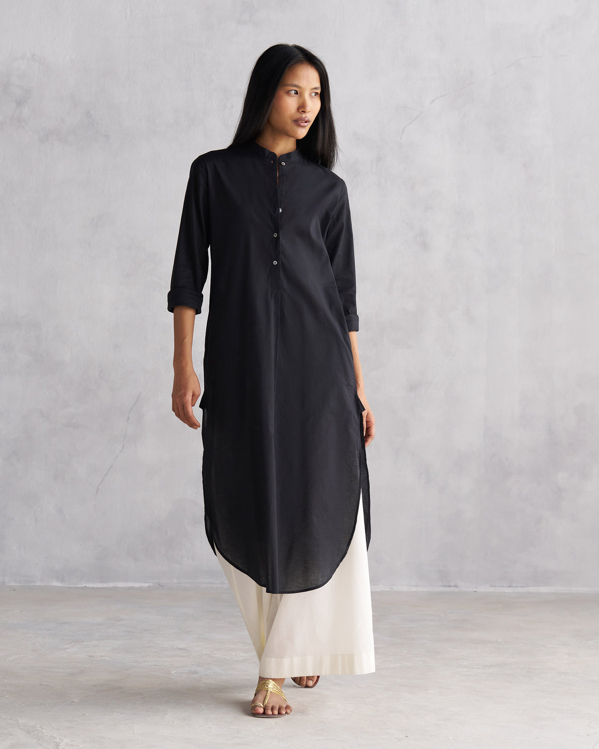 Person wearing a black long kurta with a mandarin collar and high-low hem.