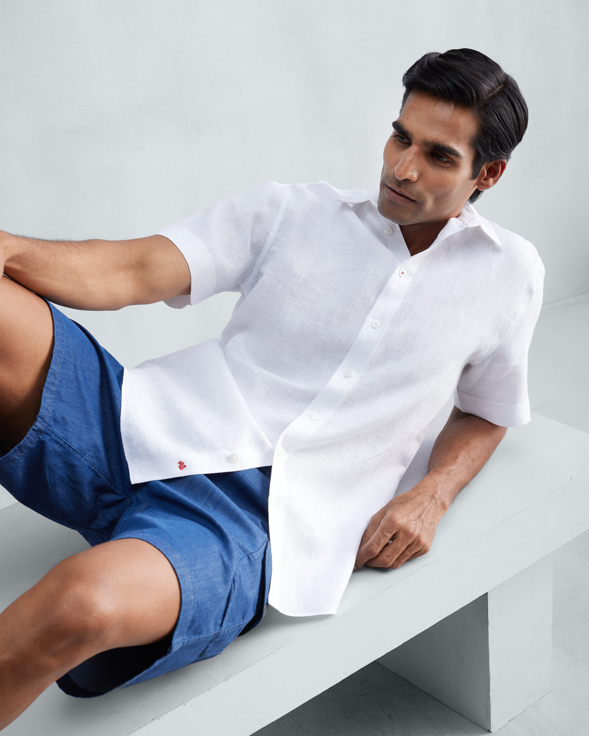 Person wearing a white half-sleeve shirt with red hem embroidery.