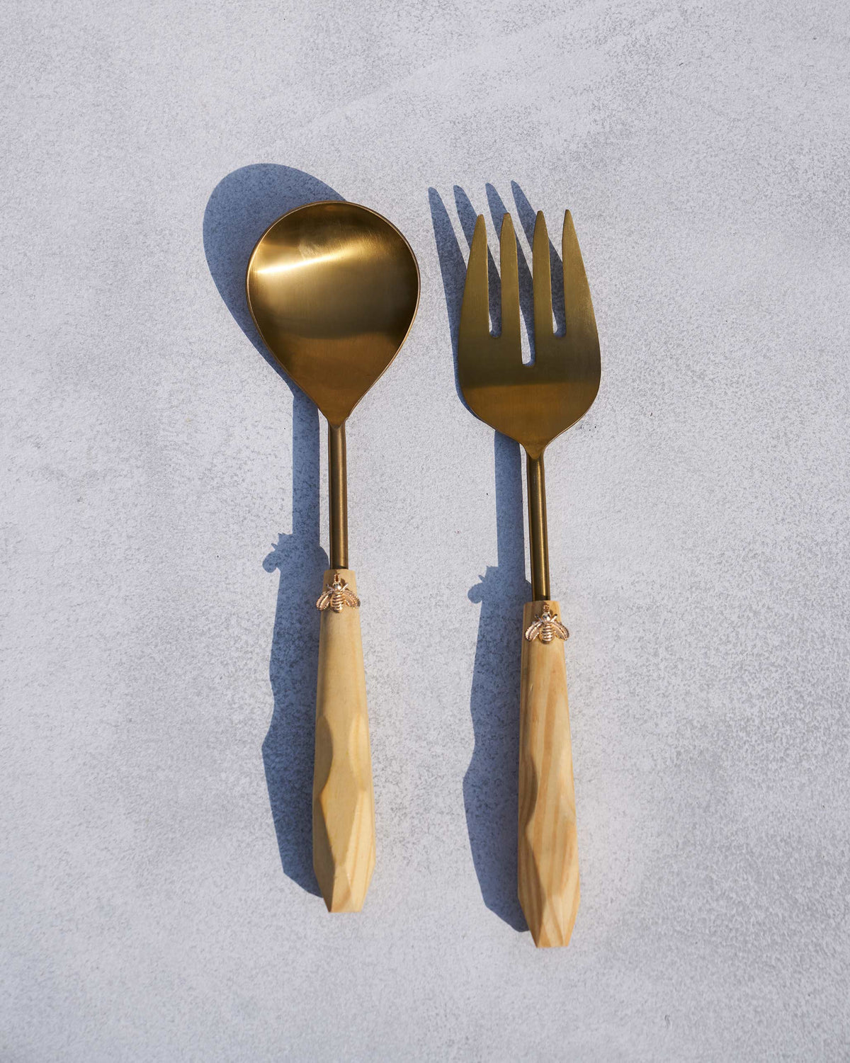 Pair of Bee Salad Servers laid flat with gold bee motifs on the handles.